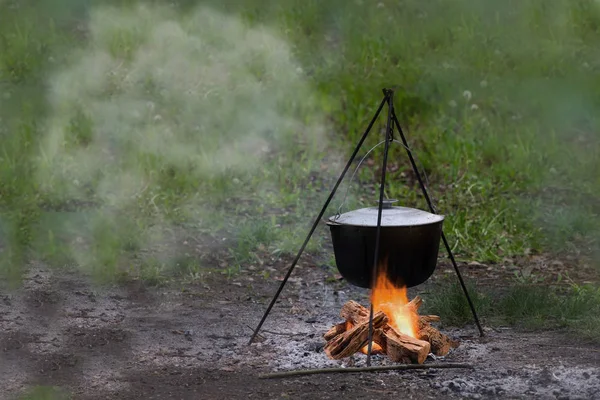 Outdoor country side cuisine with cauldron metal pot kettle for cooking outdoor in the middle of the nature near the camp with the campfire, cooking at the camp fire traditional dish
