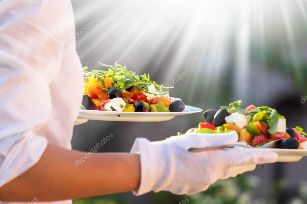 Waiter, carrying three plates with a rich salad