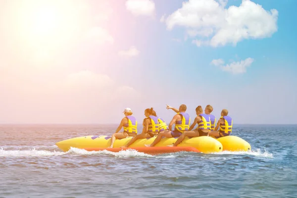 People ride on banana boat. Bright blue sea and clear sky. Happy vacation. Beach water sport