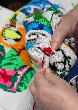 Yaşlı bir kadın parmakları embroiders. Yukarı clouse