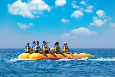 İnsanlar üzerinde muz tekne yolculuğu. Parlak mavi deniz ve açık gökyüzü. Mutlu tatil. Plaj su sporları