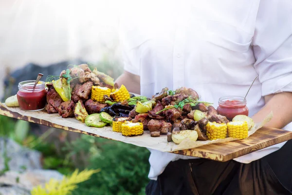 Waiter is offering grilled meat and vegetables,