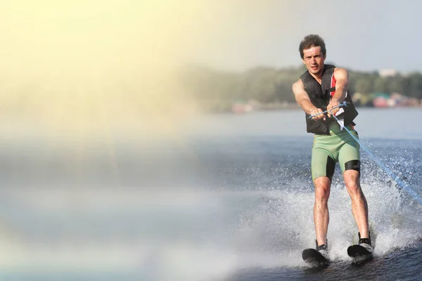 Primer plano hombre montar esquís acuáticos en el lago en verano en el día soleado. Deportes acuáticos activos. Espacio para texto — Foto de Stock