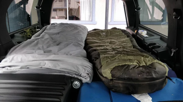 Büyük bir cipin arkasında tam boy yataklı 2 uyku tulumu. Kamp için hazır.