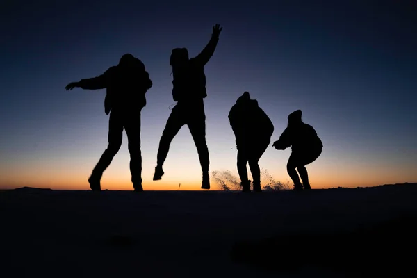 Colorado 'daki Masa Tepesi Dağı' nın tepesinde güneşin doğuşunda zıplayan 4 gencin silueti.