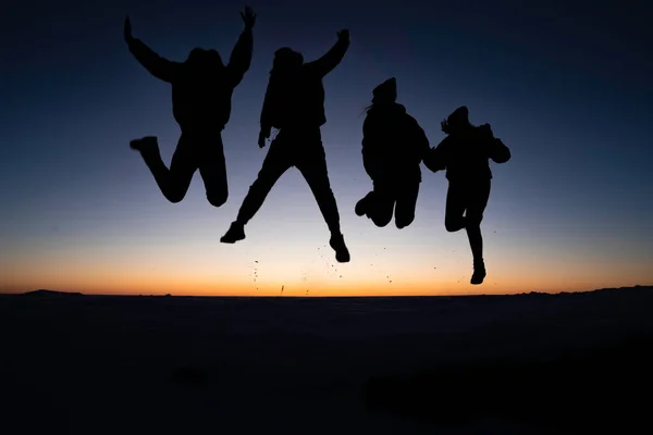 Colorado 'daki Masa Tepesi Dağı' nın tepesinde güneşin doğuşunda zıplayan 4 gencin silueti.