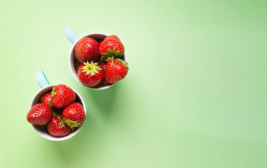 Açık yeşil arka planda, olgun çilekler, üst görünümde, yatay yönelimde, bir kopya alanı var..