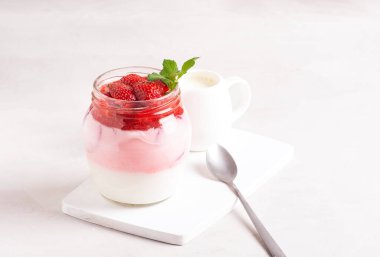 Ev yapımı kefir, çilek dilimleri, cam kavanozda nane yaprakları, sütçü ve kaşığın yanında. Sağlıklı kahvaltı kavramı.