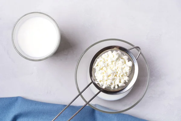 Fermented fermented milk drink kefir with kefir grains. Homemade kefir stands in a glass, next to kefir grains on a gray background, next to a blue towel. Horizontal orientation.