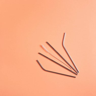 Metal yeniden kullanılabilir içecek pipetleri şeftali yüzeyinde yatıyor, sıfır atık kavramı.
