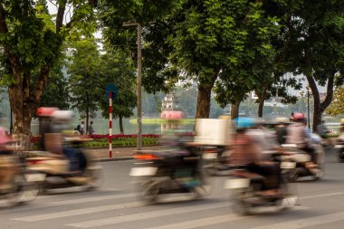 Motosiklet trafiği Hanoi 'nin eski mahallesinde Hoan Kiem Gölü' nün yanında arka planda Kaplumbağa Kulesi ile birlikte ilerliyor.