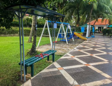 Bankta sosyal uzaklığı kırmızı haçları olan boş bir çocuk parkı ve Bintaro, Tangerang, Jakarta, Endonezya 'da çocuk salıncağı. Siyah işaretin tercümesi: 