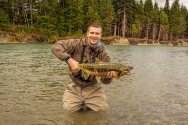 Neşeli bir balıkçı, Britanya Kolumbiyası 'ndaki Kitimat Nehri' nde bir Chum Salmon avını gururla bekletiyor.