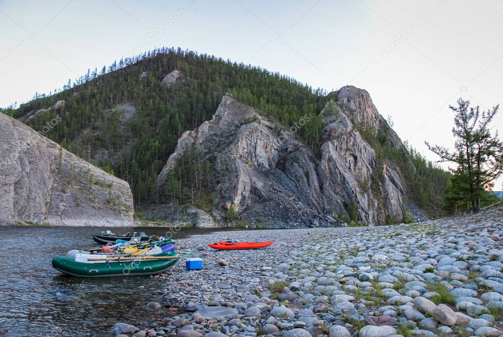 Fishing rafts and kayaks on a gravel bank on the Delger Moron river, in a canyon or gorge, in Mongolia
