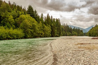 Yukarı Kitimat, buzul yeşili nehir, bulutlu bir yaz gününde, yağmur ormanları ve çakıl barları, British Columbia, Kanada