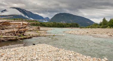 Shames ve Skeena Nehri 'ndeki kütük reçeli, bulutlu bir günde, arka planda orman ve dağlarla.