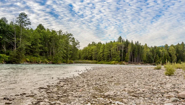 Kuzey Britanya Kolumbiyası, Kanada 'da Kitimat Nehri' nin yukarısında gün batımı bulutlu mavi gökyüzü, daha güvenli ormanlık ve çakıl barlarıyla.
