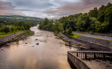 Pitlochry Barajı 'ndan gün batımında Tummel Nehri' nin aşağısında bulutlu bir yaz akşamında İskoçya, Pitlochry 'de