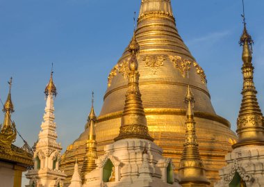 Akşam ışığı Yangon 'daki altın Shwedagon Pagoda' ya düşüyor, mavi bir gökyüzü arka planıyla.