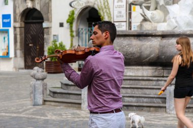 Ljubljana, Slovenya - 16 Temmuz 2018: Mestni Trg, Ljubljana Town Square 'de Robba çeşmesinin yanında çalan bir kemancı