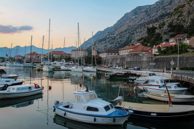 Limanda teknelerle gün batımında, Eski Kotor Kasabası 'nda, arka planda şehir duvarlarıyla, Karadağ