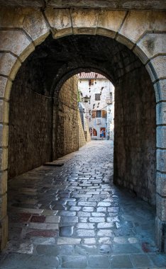Eski Kotor kasabasında arka planda uçan süpürgelerle dolu bir ara sokak, Karadağ