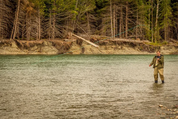 一名男子在加拿大不列颠哥伦比亚省的Kitimat河里涉水时 用苍蝇钓到了一条鲑鱼 — 图库照片