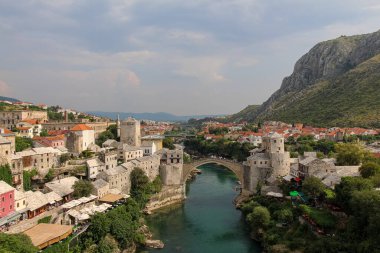 Neretva Nehri üzerindeki eski kemerli köprüyle eski Mostar kentinin manzara manzarası, arkada Hum Hill, Bosna-Hersek