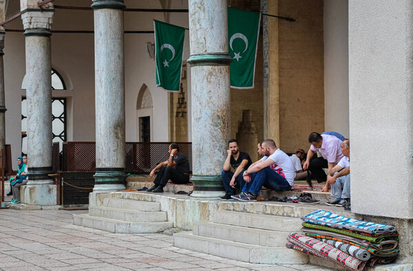 Сараево, Босния и Герцеговина - 3 июля 2018 года: мусульмане, сидящие возле медресе Гази Хусрев-бега, в районе Баскарсии, в старом городе Сараево, Босния и Герцеговина