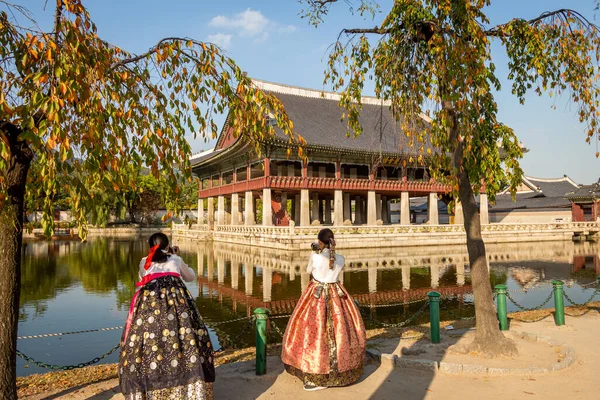 stock image Seoul, South Korea - October 19th 2017: Women dressed in hanbok traditional dresses by the lake at Gyeongbokgung Palace, Seoul, South Korea
