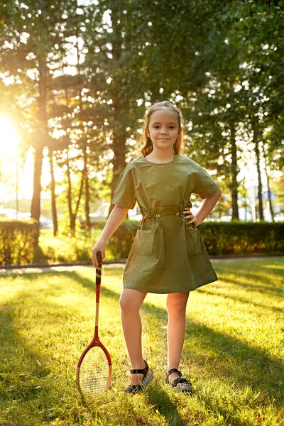 Uma menina fica em um gramado verde com uma raquete de badminton — Fotografia de Stock
