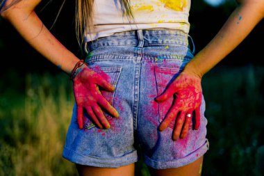 palms painted with Holi paint close up on the ass.