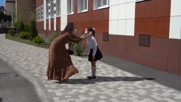 Young mother puts a mask on a child at school — Stock Video