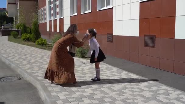 Giovane madre mette una maschera su un bambino a scuola. — Video Stock