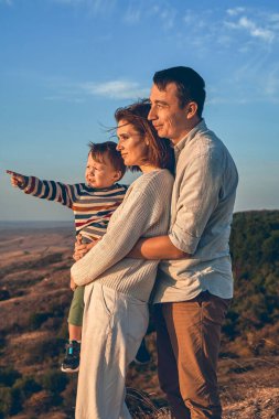 Sonbahar yürüyüşüne çıkmış küçük bir çocuğu olan güzel bir aile.