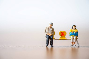 Yaşlı adam ve kadın minyatür insanlar yüz maskesi takıyor ve COVID-19 Corona salgını salgınının yayılmasını önlemek için halka mesafeli davranıyorlar. Sosyal uzaklık kavramı.