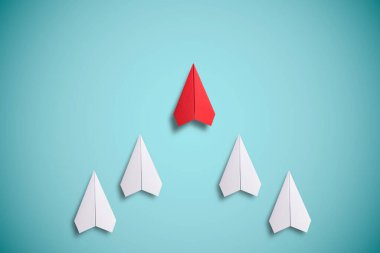 Beyaz kağıdın önünde kırmızı kağıt uçuyor. Liderlik kavramı.