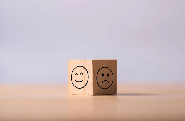 Two opposite side of emotion of happy and sad which print screen on wooden cubic. Customer experience survey and satisfaction feedback concept.