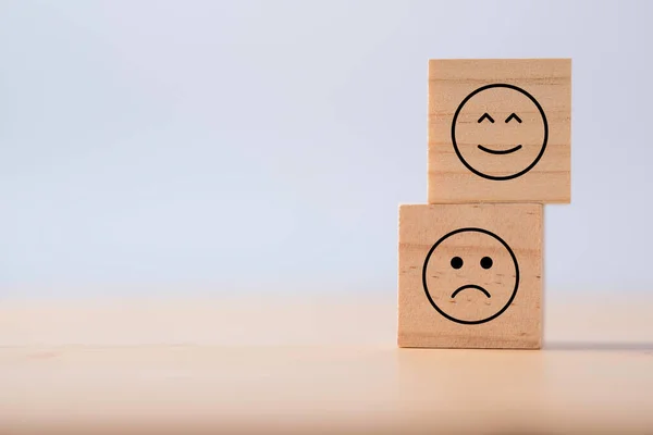 Two emotions of happy and sad which print screen on wooden cubic. Customer experience survey and satisfaction feedback concept.
