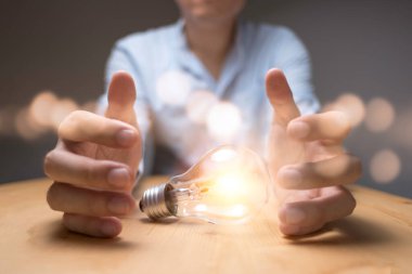 İş adamı elinde turuncu ışıklı bir ampul tutuyor. Yaratıcı yeni iş fikri kavramı.