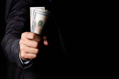 Siyah arka planda Amerikan doları banknotunu elinde tutan bir işadamı. USD dünyanın ana döviz kurudur..