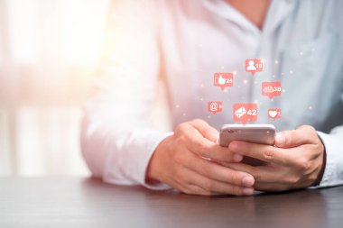Akıllı telefonlu bir iş adamı, aşk ve yıldız gibi sosyal medya simgelerini kullanmak için elinde tutuyor. Pazarlama ve iş konsepti.