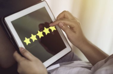 Müşteri hizmetleri değerlendirmesinde sarı yıldızları arttırmak için tablet bilgisayara dokunan kadın..
