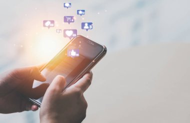 Sosyal medya ve internet alışveriş simgeleriyle iletişim kurmak için cep telefonuna dokunan bir kadın. Mesela kalp, e-posta, alışveriş arabası, yıldız ve mesaj gibi. Dijital ve çevrimiçi pazarlama kavramı.