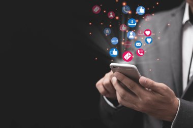 Sosyal medya ve pazarlama kavramı, beyaz akıllı telefon tutan ve renkli sosyal medya simgeleri kullanan iş adamı.