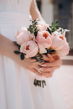 Gelinin elinde güzel bir buket. Gelin buketini tutuyor. Kadınların elinde pembe şakayık gülleri