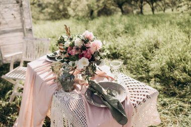 Yaz bahçesinde iki kişilik güzel bir düğün masası. Şenlik masasında renkli şakayık buketi ve güller