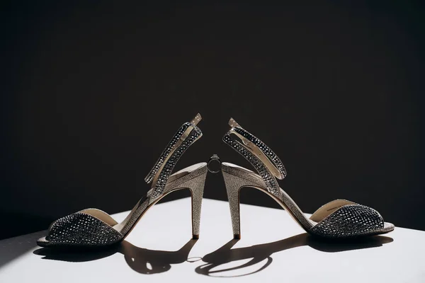 pair of stylish women's high heeled shoes with shiny crystals and with ring between them. close up women's high heeled shoes