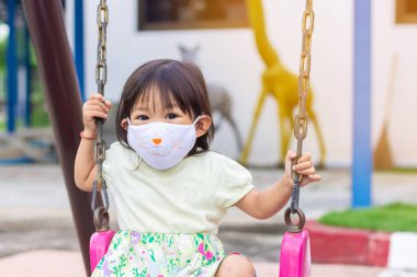 Yalnız Asyalı küçük kız oyun alanında top oynayıp tekmeliyor. 2 yaşında bir bebek. Sağlık için egzersiz. Spor ve çocuk konsepti.