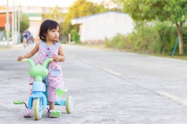  2-3 yaşlarında bir bebeğin portresi. Çocuk parkında bisiklet sürmek için oynayan ve pratik yapan mutlu Asyalı kız çocuğu. Gülümsüyor ve gülüyor.